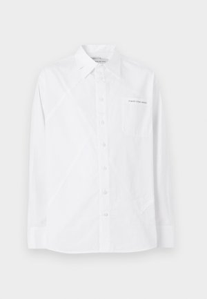 Chemise blanche à manches longues en coton, avec un devant à boutons, une poche poitrine et des détails de couture diagonale.