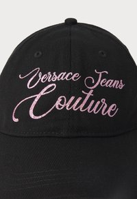 Boné preto com textura ribeteada, apresentando um bordado brilhante em rosa de "Versace Jeans Couture" na frente. Aba curva com furos de ventilação.