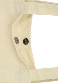 Zbliżenie beżowej torby z klapką na zatrzask i szczegółowym przeszyciem. Uchwyt torby jest widoczny po prawej stronie.