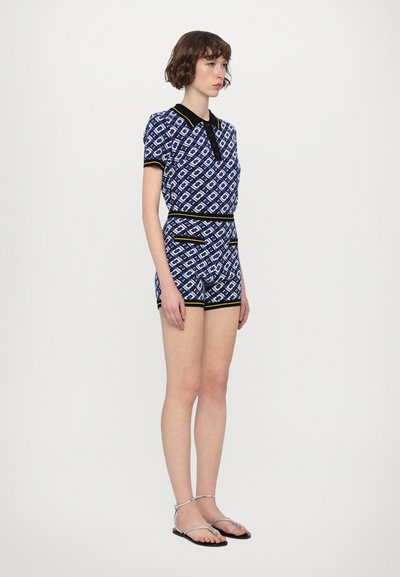 Ensemble deux pièces à motifs bleus avec des manches courtes et un short, présentant un col et des finitions noirs avec des accents jaunes. Tissu léger.