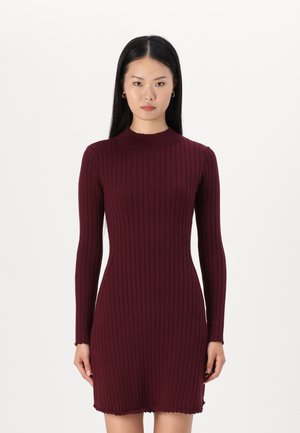 Burgundy ribbed knit dress with a fitted silhouette, high neckline, and long sleeves. Features a scalloped hem and smooth texture.