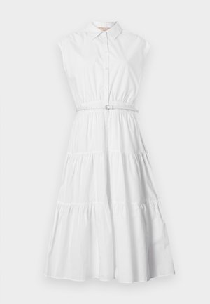 Λευκό αμάνικο φόρεμα με πολυεπίπεδη φούστα, κουμπιά μπροστά, γιακά και λεπτή ζώνη στη μέση σε απλό φόντο.