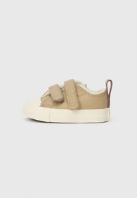 Pulka ādas toddler kedas ar diviem Velcro siksnām, krēmveida iekšējā oderē un baltu gumijas zoli. Apaļš purngals un aizmugures cilpa detaļa.