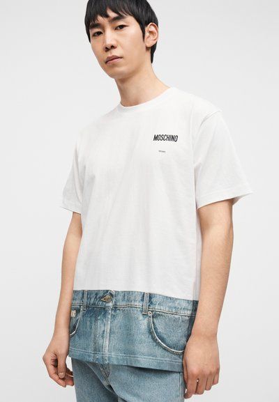 Λευκό βαμβακερό T-shirt με εκτύπωση τζιν στο κάτω τελείωμα, με λογότυπο "Moschino Milano" στο πάνω αριστερό μέρος. Κοντά μανίκια.