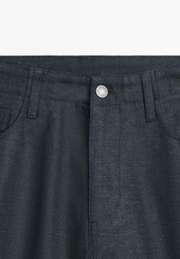 Donkerblauwe spijkerbroek met riemlussen, voorzakken en een zilveren knoopsluiting in de tailleband.