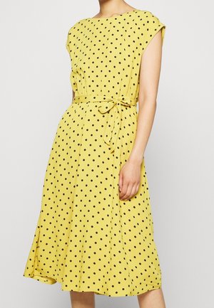 Robe jaune à pois avec un col rond, des manches courtes, une taille cintrée et une ceinture à nouer, présentant une jupe fluide, arrivant au genou.