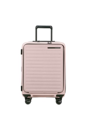 Pink hard-shell suitcase with horizontal ribbed texture, black accents, and retractable handle, featuring four smooth-rolling wheels.