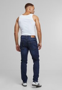 Mørkeblå skinny jeans laget av denim, med en brun lærpatch i livet, med en tettsittende design og diskret baklommesting.