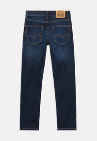 Vaqueros de mezclilla azul oscuro con corte ajustado, que cuentan con una cintura alta, detalles de costura y dos bolsillos traseros decorativos con formas puntiagudas.