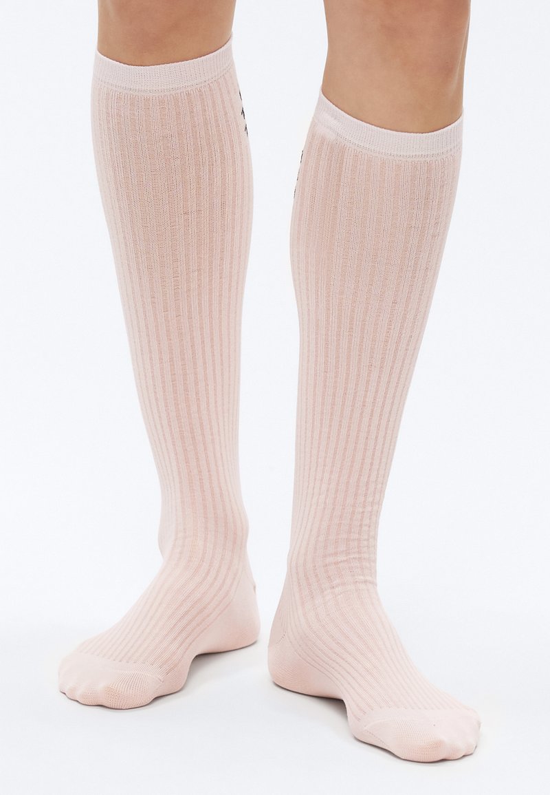 Ponožky po kolená v svetloružovej farbe s rebrovanou textúrou a priliehavým strihom. Materiál pôsobí mäkko a elasticky, vhodný na pohodlné nosenie.