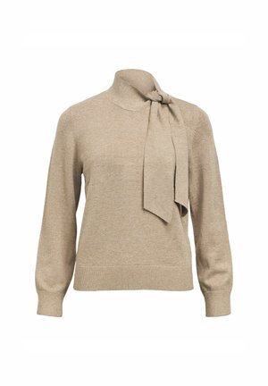 Beige langarm gebreide trui met hoge kraag en een vastgemaakte brede sjaal die aan de linkerkant in een knoop is gestrikt.