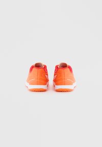 Des chaussures de sport orange avec une tige en maille, un col rembourré et des semelles blanches présentent des motifs texturés et des accents d'une teinte orange plus foncée.