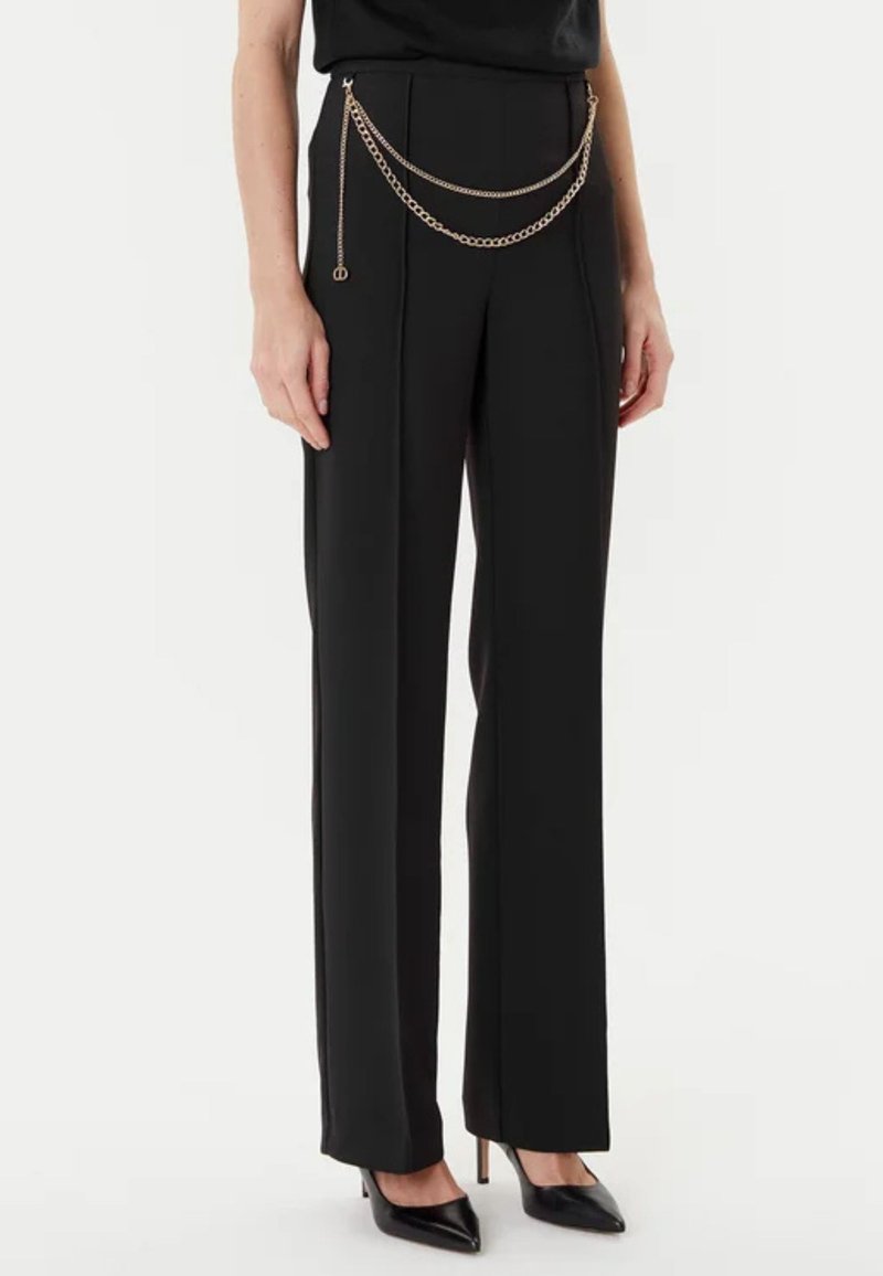 I pantaloni neri a vita alta presentano gambe dritte, un tessuto testurizzato e un accento decorativo in catena d'oro in vita.