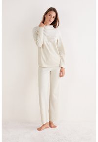 Gezellig tweedelig loungewear-set in zachte crèmekleurige stof met een top met hoge hals en sneeuwvlokmotieven en een rechte broek.