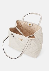 Biała pikowana torba na ramię ze złotymi elementami, pojemnym wnętrzem i charakterystycznym wzorem z logo. Posiada dwie rączki i zapięcie na zatrzask.