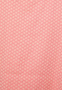 Têxtil com um padrão repetido de formas rosa claro sobre um fundo rosa mais escuro. Textura macia com um acabamento mate.