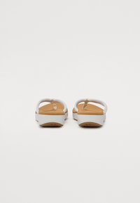White flip-flops with a solid brown footbed, featuring thick straps and a slight heel. The sole has a textured pattern for grip.