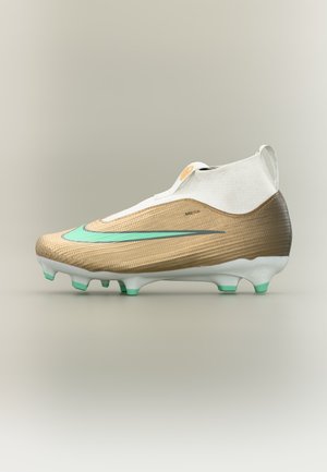 Chaussure de football dorée et blanche avec le logo Nike turquoise, col haut à la cheville et semelle blanche avec crampons turquoise sur fond beige.