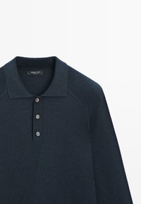 Polo en maille à manches longues de couleur bleu marine foncé, avec trois boutons et des détails côtelés aux épaules, col rabattable.