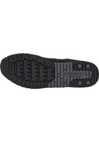 Schwarze Sneaker-Sohle mit einem strukturierten Gummidesign, tiefen Rillen und zwei runden Akzenten. Markenname "hummel" ist in Grau sichtbar.