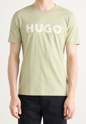 Oliwkowa bawełniana koszulka z napisem "HUGO" wytłuszczonymi białymi literami na piersi. Krótkie rękawy i okrągły dekolt.
