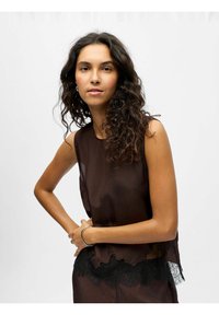 Top senza maniche marrone e trasparente con bordi scallopati e dettagli in pizzo nero sull'orlo. Tessuto morbido, vestibilità rilassata e design minimale.