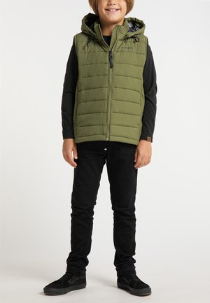 Gilet imbottito verde oliva con cappuccio, chiusura frontale con zip e coulisse elastiche. Indossato sopra una maglietta a maniche lunghe nera e pantaloni neri.