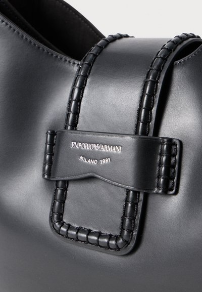 Borsa a spalla in pelle nera con tracolla intrecciata, placca logo in argento e texture liscia. Design semplice e moderno con linee pulite.