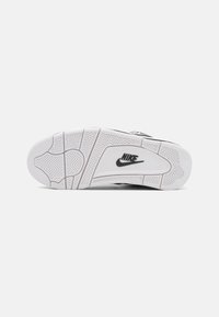 Nike-sneakersula i svart och vitt, med texturerat greppmönster, gummimaterial och en framträdande Nike-logotyp.