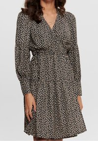 Kleid mit floralem Druck in Schwarz und Cream, mit langen Ärmeln, tailliertem Schnitt und mehrlagigem Rock. Hergestellt aus leichtem Stoff.