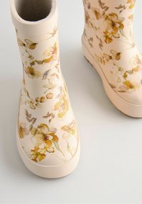 Bottes en caoutchouc à motif floral, de couleur beige doux, avec des accents jaunes et verts. Semelles texturées pour une meilleure adhérence, avec un design à bout arrondi.