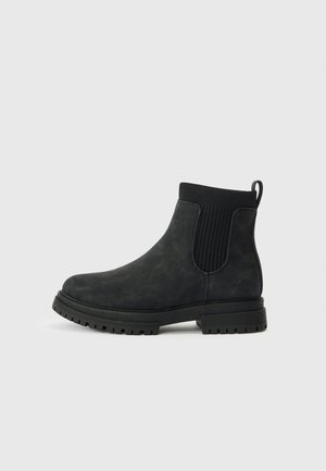 Bottes noires à la cheville avec une finition mate lisse, des panneaux latéraux élastiques et une semelle extérieure en caoutchouc robuste pour une bonne traction. Talon renforcé et détail avec logo.