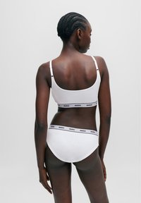 Bralette e mutandine in cotone bianco con banda logata nera "HUGO". Design semplice, spalline regolabili, forma aderente e texture morbida.