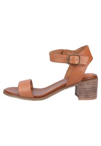 Sandalia de cuero marrón clara con tira en el tobillo, punta abierta y tacón de madera grueso. Diseño simple con una textura suave y detalle de hebilla ajustable.