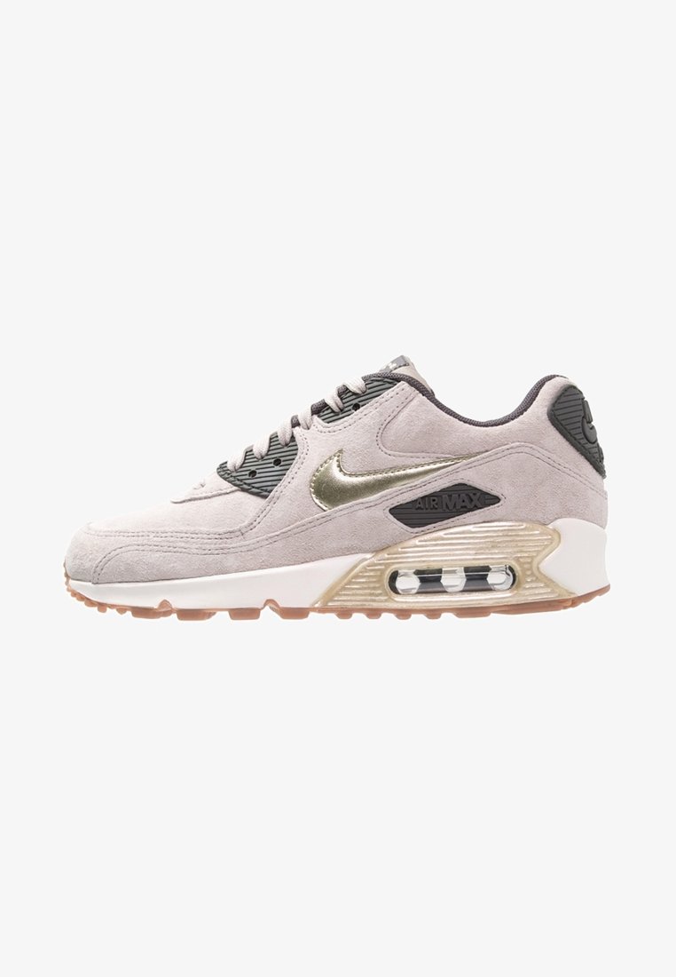 Světlé šedé semišové tenisky se lesklým zlatým logem, texturovanými černými detaily, bílou mezipodešví a průhledným Air Max odpružením. Gumová podešev.