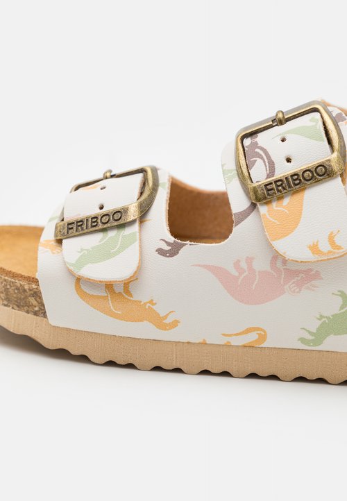 Sandalo bianco con motivo, caratterizzato da grafiche di dinosauri colorate, due fibbie regolabili, suola in sughero e battistrada texturizzato per una buona aderenza.