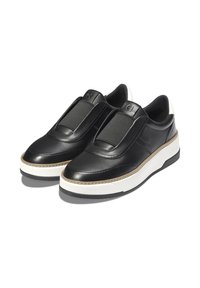 Schwarze Leder Slip-On Sneakers mit weißen Plateausohlen und elastischen Paneelen oben, vor weißem Hintergrund.