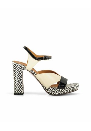 Sandale à talon haut avec plateforme et talon à motif géométrique noir et blanc, brides en cuir crème et noir, et boucle à la cheville.