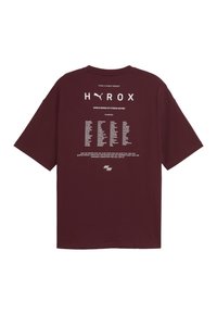 Bordeaux farbenes Baumwoll-T-Shirt mit kurzen Ärmeln. Der Rücken zeigt weiße Schrift mit den Veranstaltungsdetails und ein Logo am unteren Rand. Klassisches Rundhalsdesign.
