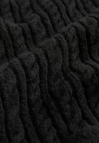 Czarna dziana tkanina z teksturowanym wzorem w warkocze. Miękka, puszysta textura, eksponująca podniesione elementy wzornicze na płaskim tle.