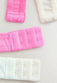 Drie haak-en-oog banden van stof in roze en wit. De roze band heeft een gestructureerde afwerking, terwijl de witte glad is met ronde hoeken.