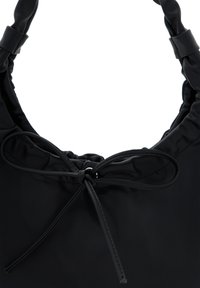 Fekete nylon táska lekerekített tetejével, redőzött kialakítással és megkötött masni részlettel. Simaság és minimalista stílus jellemzi.