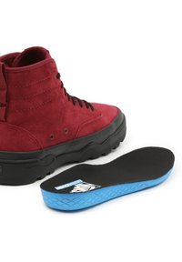 Baskets montantes en daim rouge avec semelle en caoutchouc noire. Comprend une semelle intérieure noire amovible avec fond bleu et surface antidérapante texturée.