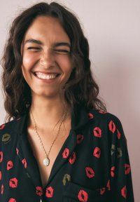 Mustmust mustade mustvetek must järved mustpunaste ja kuldsete huulte mustriga, mille peal on kuldne kaelakee, millel on ovaalne ripats. Subjekt naeratab, tal on laineline pruun juuksed.