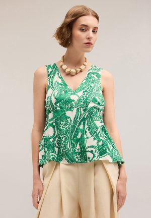 Top senza maniche verde e bianco con design a V, caratterizzato da una caduta fluida e impreziosito da una collana con grandi perline.