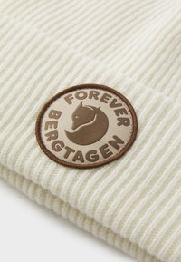 Cream-colored ribbed knit fabric with a circular brown patch featuring a fox head and the words "FOREVER BERGTAGEN."