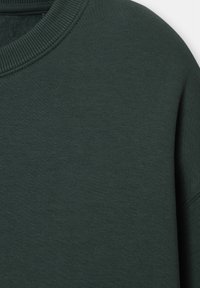 Sweat-shirt vert foncé à col rond montrant un col côtelé et une texture de tissu lisse.