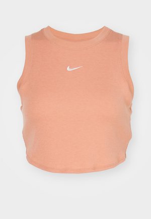 Svetlo broskyňový crop top bez rukávov vyrobený z rebrovanej látky, s okrúhlym výstrihom a malým bielym logom Nike swoosh na prednej strane.