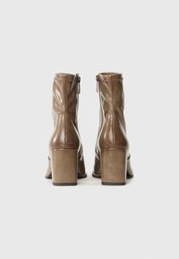 Brown leather ankle boots with a shiny finish, square heel, side zippers, and subtle stitching details.