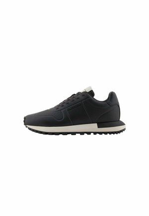 Sneaker atletici neri con una parte superiore in sintetico texturizzato, suola bianca a contrasto, punta rotonda e chiusura tradizionale con lacci.